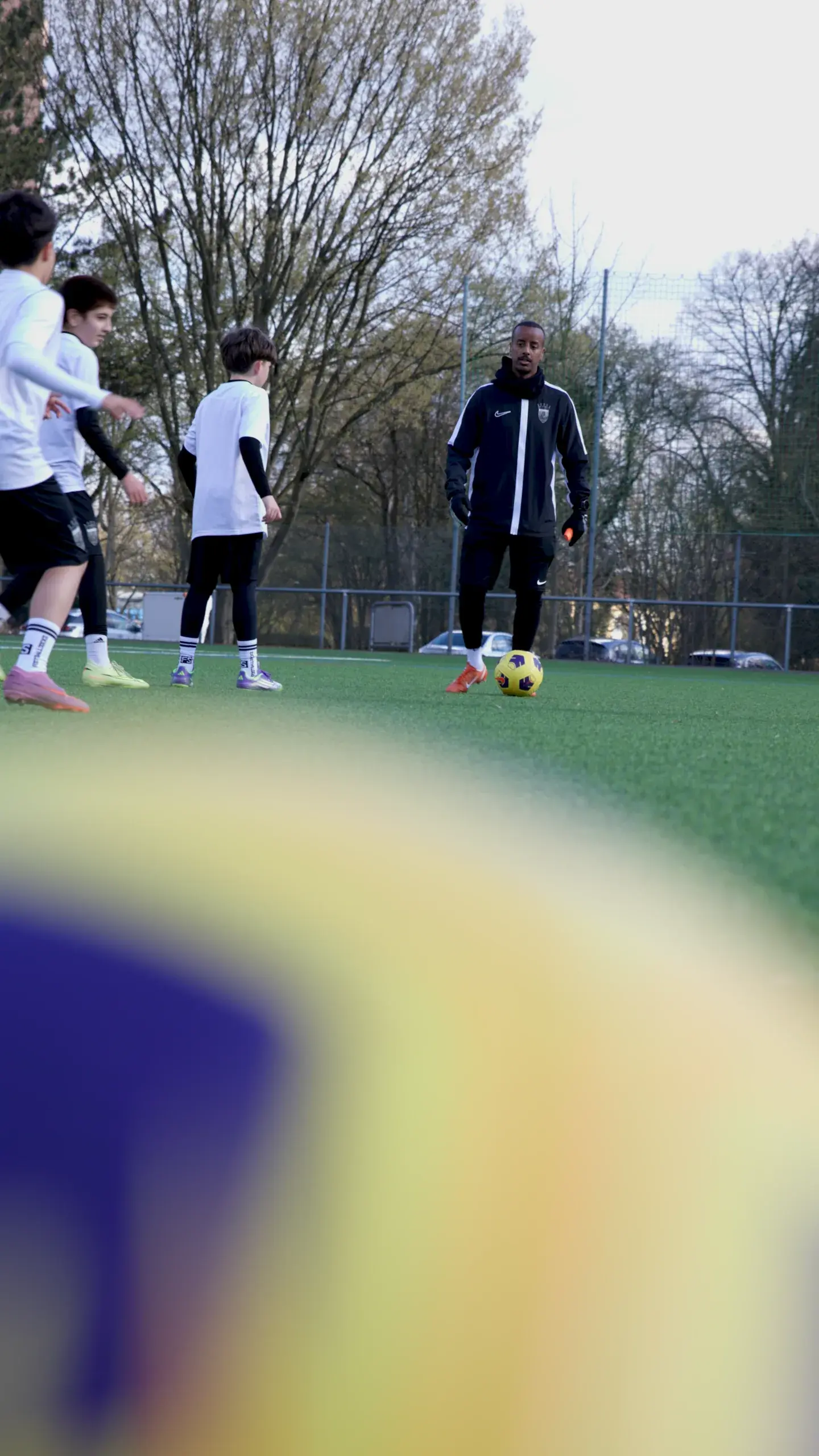 Trainer mit Ball und mehrere Spieler in Bewegung im Kleingruppentraining